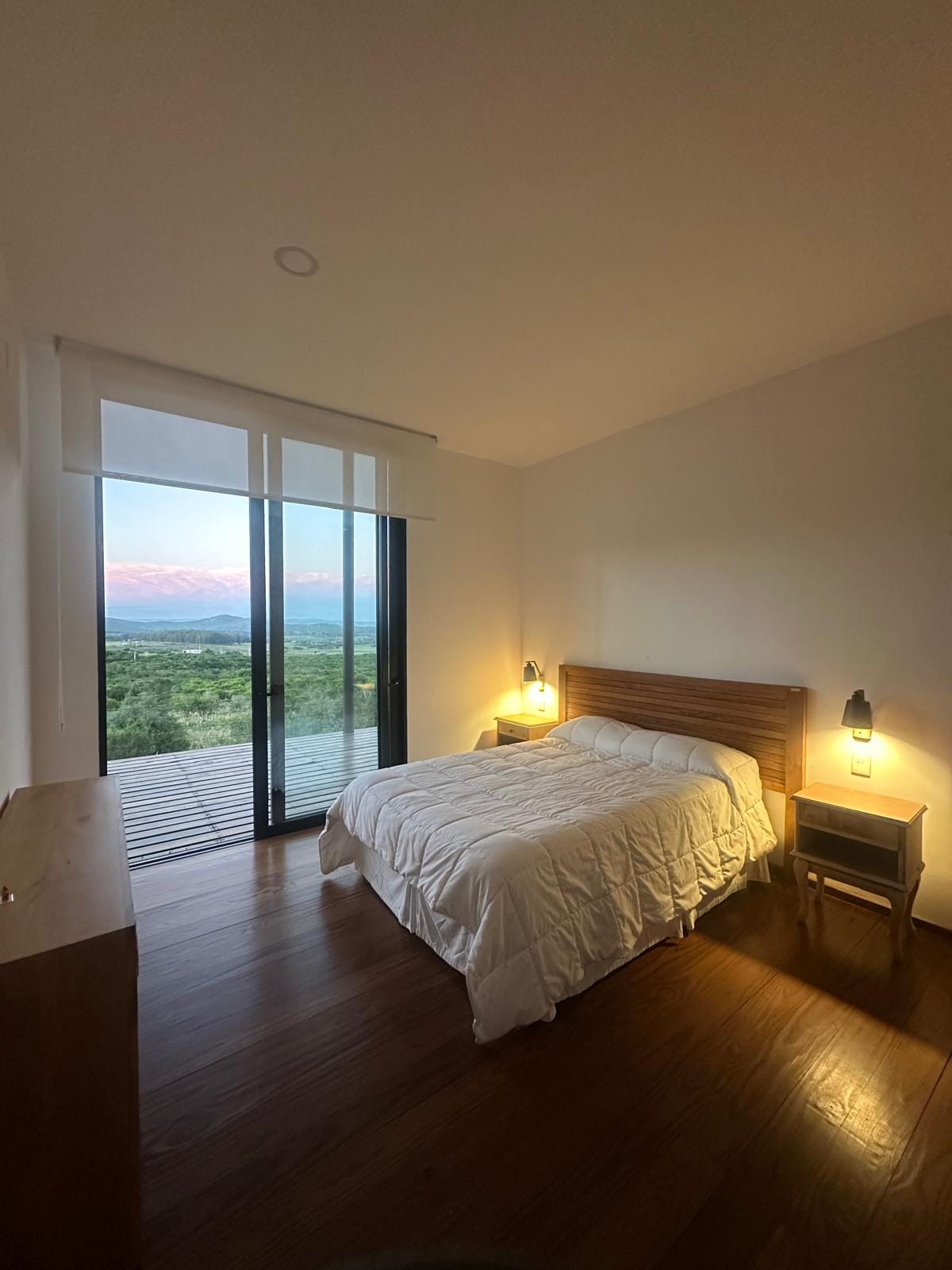 Habitación con cama doble y atardecer de fondo
